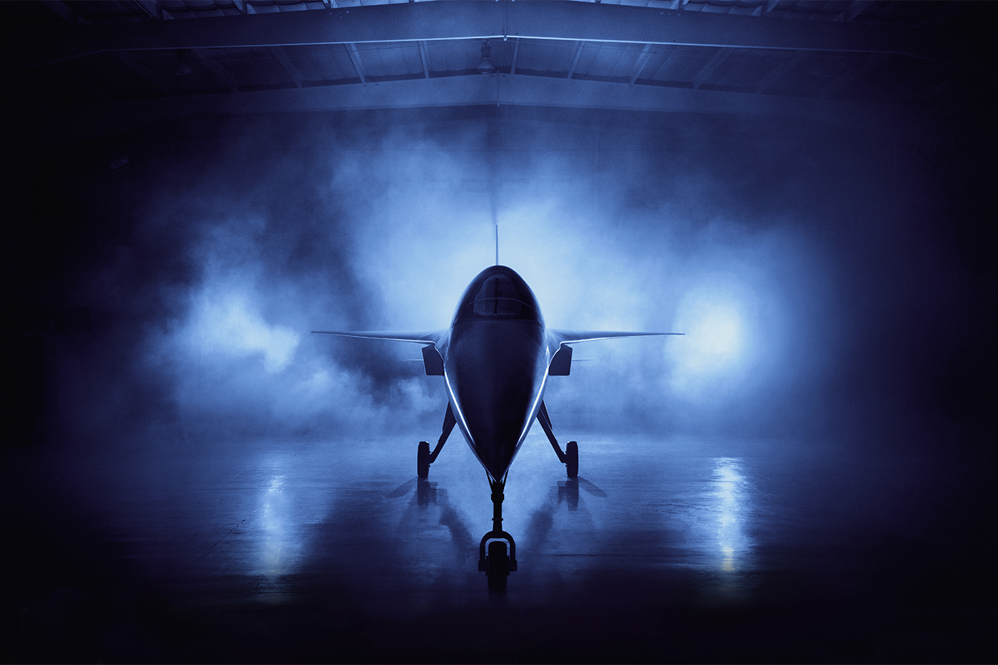 A supersonic airplane sits in a hangar surrounded by fog and illuminated by blue light.