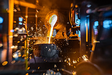 up-close of liquid metal being poured into a large metal bowl